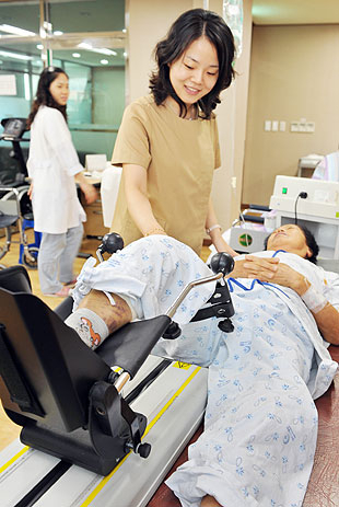 관절염 환자가 물리치료실에서 무릎을 펴는 운동을 하고 있다.