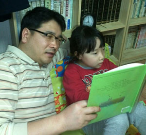 민송기 교사가 막내 경린 양과 함께 집에서 책을 읽고 있다.