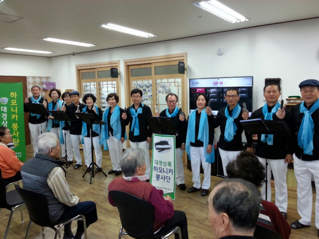 연주한 뒤 하모니카를 들고 활짝 웃고 있는 상록 봉사단원들.