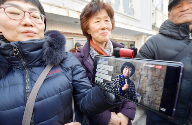 목포 근대역사문화공간 내 부동산 투기 의혹을 받는 무소속 손혜원 의원이 23일 오후 목포 현장에서 해명 기자회견을 하는 가운데 회견장 밖에서 시민들이 손 의원의 회견을 스마트폰으로 보고 있다. 연합뉴스