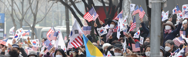 코로나19 신규 확진이 팬데믹 이후 최다를 기록한 12일 오후 서울 중구 감리교 회관 앞에서 전광훈 사랑제일교회 담임 목사가 대표로 있는 국민혁명당 주최로 열린 1천만 자유 통일 기도회에서 참석자들이 태극기와 성조기를 흔들며 찬송을 부르고 있다. 연합뉴스
