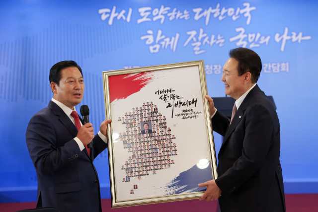 윤석열 대통령이 28일 서울 용산구 전쟁기념관 피스앤파크에서 열린 전국 시장·군수·구청장 초청 오찬간담회에서 대한민국시장·군수·구청장협의회 대표회장인 조재구 대구 남구청장으로부터 액자를 선물받고 있다. 연합뉴스