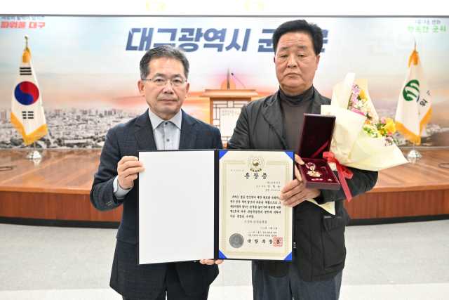 김진열(왼쪽) 대구 군위군수가 6·25 전쟁 영웅 故박재용 하사 조카 박운기(오른쪽) 씨에게 무공훈장을 전달하고 기념 사진을 촬영하고 있다. 군위군 제공